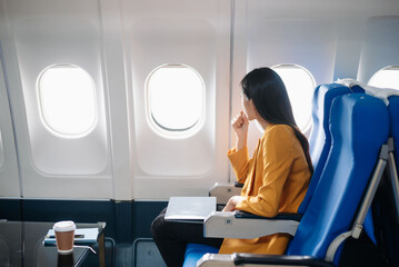 Photo of a frustrated woman sitting on an airplane with her head in her hands. Asian woman sitting