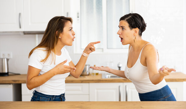 Female friends sorting out relationship. Two irritated young Latinas arguing noisily and emotionally gesturing in cozy home kitchen