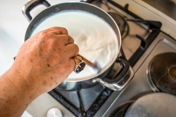 Senior chef cooking milk in a pot on a stove