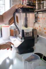 Senior woman using blender in the kitchen preparing food