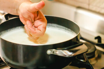 Chef checking milk temperature while cooking on stove