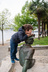 Child playing on statue by waterfront park