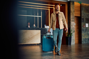 Happy traveler with suitcase leaving hotel.