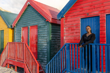 Row of brightly coloured beach huts and young woman