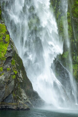 Raging waterfall and greenery of Mildford Sound, New Zealand