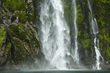 Raging waterfall and greenery of Mildford Sound, New Zealand