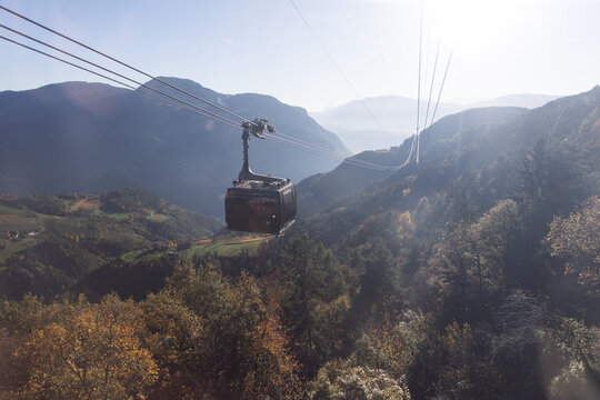 Cable car gliding above a sunlit mountain valley