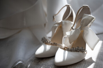 White bridal heels with jeweled straps and satin bow accents