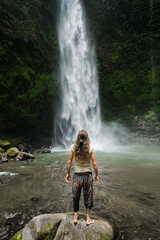 Woman with Open Arms Facing Waterfall, Surrender, Healing and Connection with Nature.