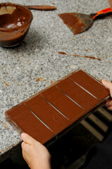 chef's hand are shaking chocolate mould to ensure the melted chocolate are spread evenly