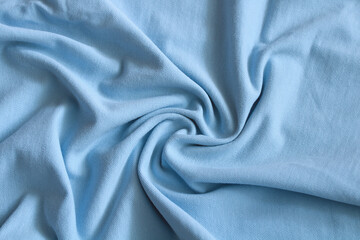 Light blue fabric texture background with soft folds and wrinkles, creating a swirl pattern