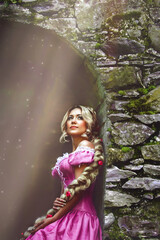 Beautiful girl with long hair braided in a braid, in corset and magnificent pink dress.