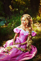 Beautiful girl with long hair braided in a braid, in corset and magnificent pink dress.