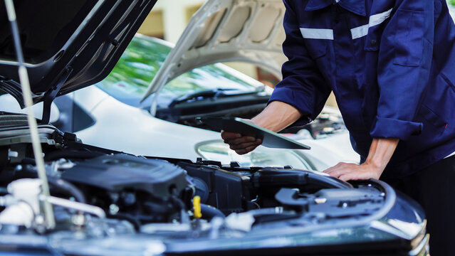 Auto mechanic hands using wrench to repair auto engine. Car maintenance, service at garage. Technician inspects vehicle for problems. Auto repair, fixing, check, services, insurance, checkup concept.