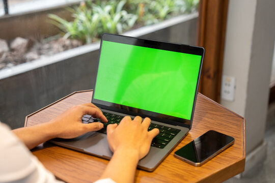 Working on a laptop with a green screen next to a phone Remote work in a modern setting