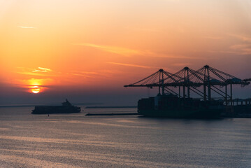 Beautiful sunset silhouette of ships and gantry cranes in the port of Jebel Ali. Golden hour in the port.