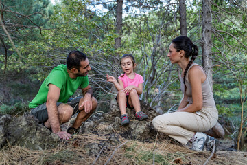 Little girl explaining something to parents during forest walk sharing thoughtful moment