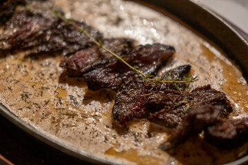 Medium rare grilled meat with gravy sauce on pan