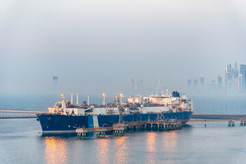 Tanker ship, LNG carrier moored in the gas terminal in the port of Jebel Ali. City skyline of Dubai...