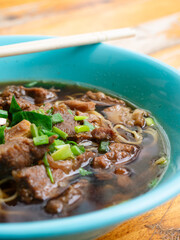 Braised beef noodle soup set on wooden table.