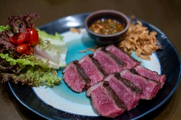 Medium rare sliced Picanha steak meat served on plate with vegetable
