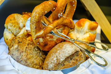 Freshly baked bread assortment displayed in a silver basket at a cozy bakery in the morning light
