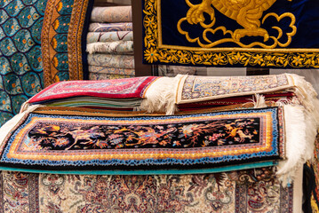 Interior of a shop filled with Iranian silk carpets in various colors and intricate patterns,...