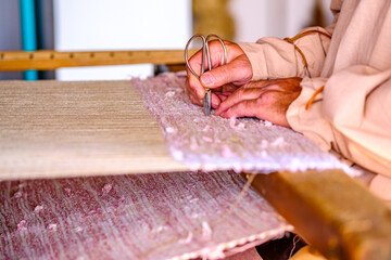 Hands skillfully weave fabric on a loom, showcasing traditional craftsmanship in a serene workshop...