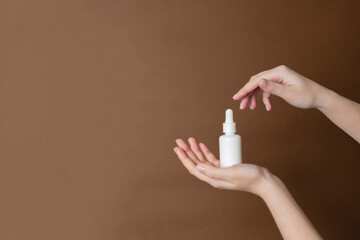 Serum glass unbranded tube or essential oil with pipette on brown background. Persenting luxury skincare products