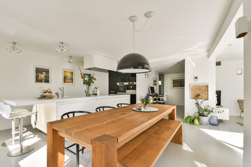 A spacious and stylish modern kitchen design featuring a wooden dining table, sleek appliances, and vibrant floral accents, creating a warm atmosphere.
