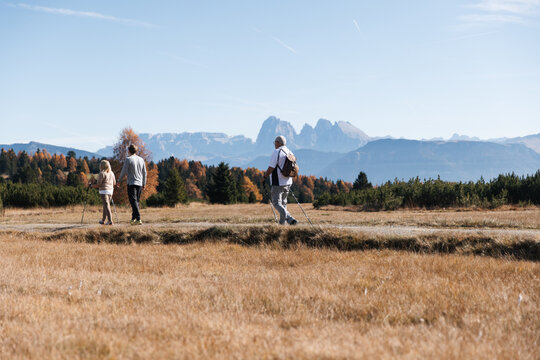 Three hikers walking toward Dolomites in South Tyrol