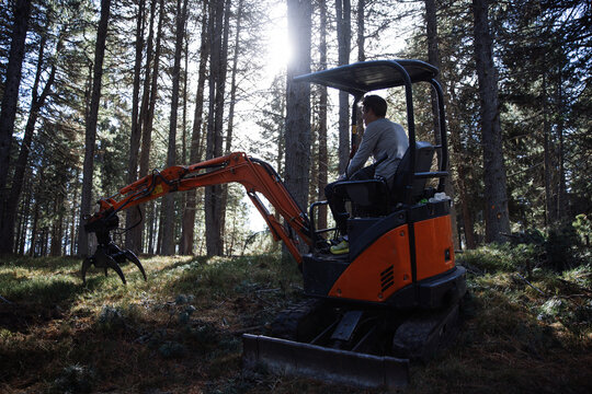 Man operating mini excavator in South Tyrol forest