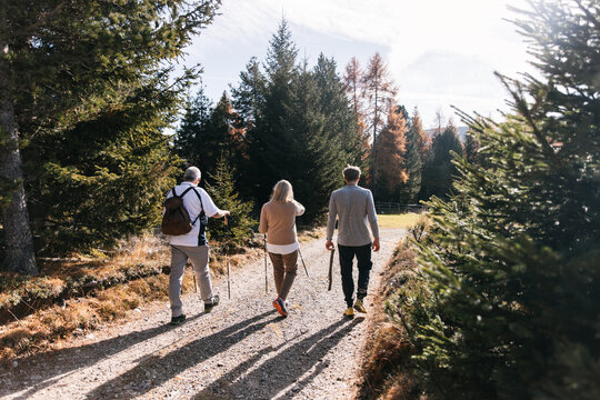 Three hikers walk sunlit path in South Tyrol, Dolomites