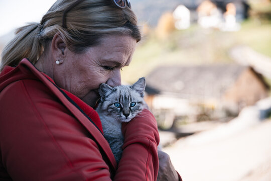 Woman cuddles blue-eyed kitten outdoors in soft natural light