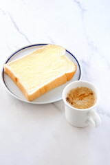 マーガリンを塗った厚切りパンと、淹れたてで香りのよいコーヒーで、朝食のイメージ
