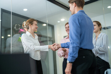Business professionals engage in a handshake during a collaborative meeting in a modern office space
