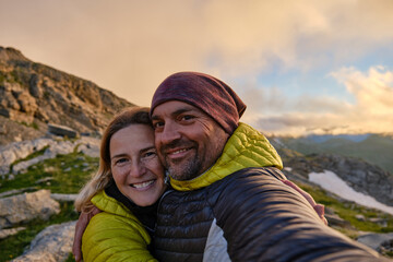 Couple embracing taking a selfie in the mountains during sunset