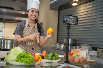 A female chef broadcasts her cooking knowledge live on a social media app on her mobile phone.