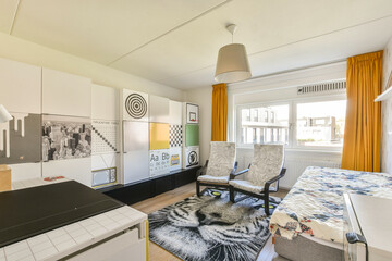 A stylish bedroom featuring contemporary furnishings, large windows for natural light, and a blend of patterns and textures that create a cozy atmosphere.
