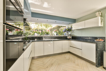 A contemporary kitchen design featuring sleek cabinetry and a beautiful view of flowering plants through large windows, creating an inviting and stylish cooking space.