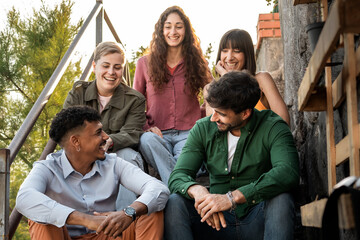 Diverse friends enjoying conversation and laughing on outdoor steps