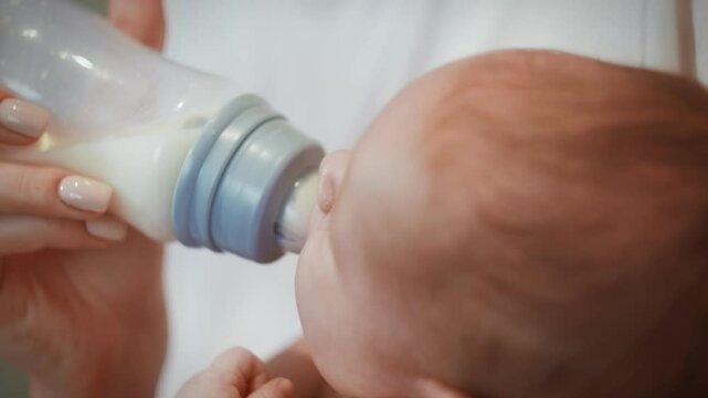 Mother feeds the baby from a bottle with a pacifier.
