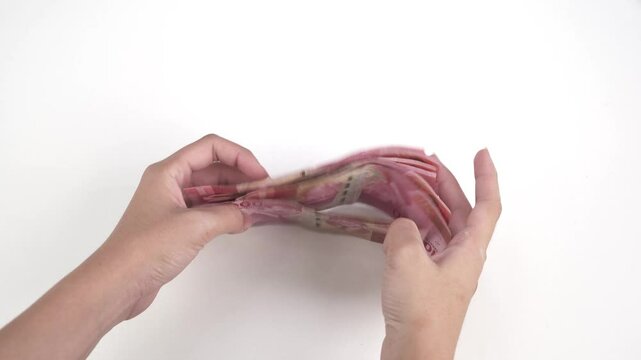 Footage video of hand picks up Republic of Indonesia money in one hundred thousand rupiah denominations scattered on the table and tidies it up