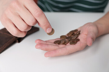 Man counting coins at white table, closeup. Financial problems