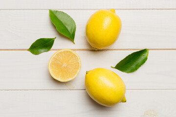 Many fresh ripe lemons with green leaves on colored background, top view, space for text