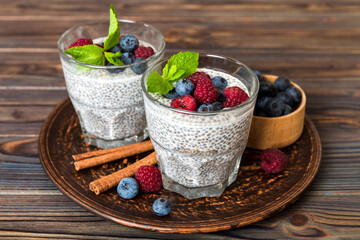 Healthy breakfast or morning with chia seeds vanilla pudding raspberry and blueberry berries on table background, vegetarian food, diet and health concept. Chia pudding with raspberry and blueberry