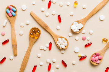 Vitamin capsules in a spoon on a colored background. Pills served as a healthy meal. Red soft gel vitamin supplement capsules on spoon