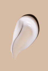 smear of creamy white texture cosmetic sample close up on beige background