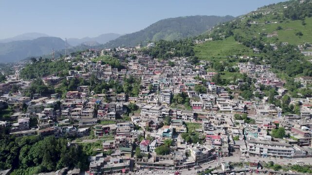 rial view of a densely populated town built across a green hillside