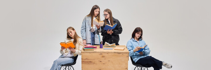 Group of teenage girls in classroom, wearing casual outfits and actively participating in reading...